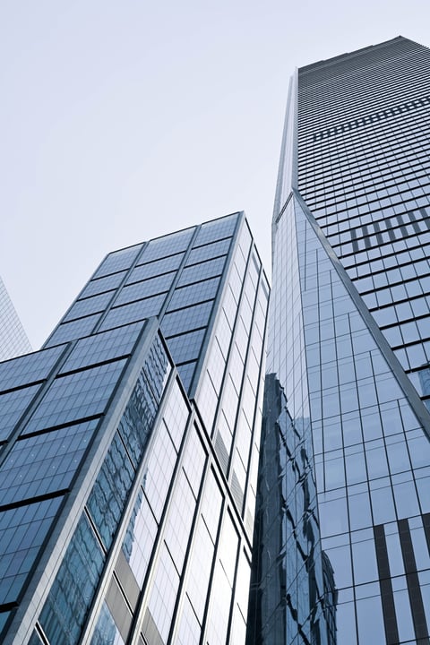 Looking up at glass-and-steel skyscrapers converging against a pale sky.