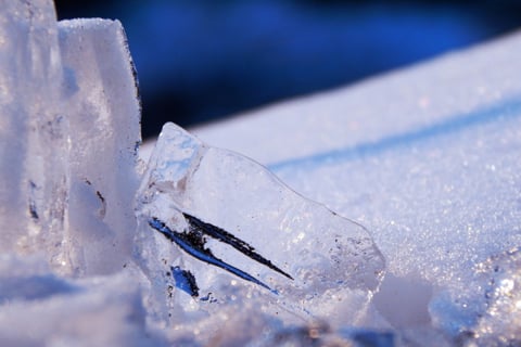 Close-up of ice crystals and frozen texture in blue light.
