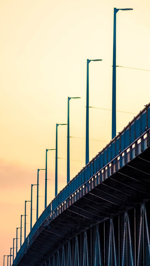 Tall bridge lamps receding into a pale sky.