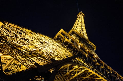 The Eiffel Tower lit at night against a dark sky.